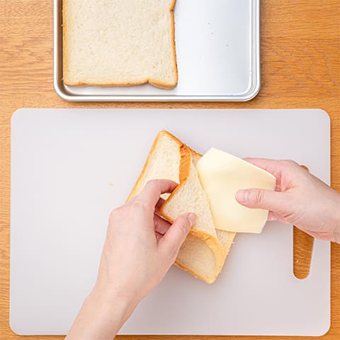 <1>の食パンの切り込みに、スライスチーズを挟みこむ。